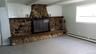 Unfurnished living room featuring beam ceiling, a stone fireplace, and a baseboard radiator
