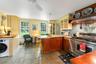 Kitchen featuring range with two ovens, washer / dryer,microwave, custom exhaust hood, and a peninsula