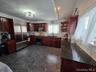 Kitchen with glass insert cabinets, dark brown cabinets, stainless steel appliances, tasteful backsplash, and dark stone counters