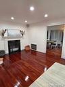 Living room featuring a glass covered fireplace, dark wood finished floors, recessed lighting, and heating unit