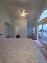 Bedroom featuring high vaulted ceiling, dark wood-style floors, access to exterior, and a ceiling fan