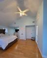Bedroom with light wood-style flooring, high vaulted ceiling, two closets, and a ceiling fan