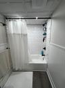 Bathroom featuring shower / tub combo, dark wood-type flooring, and wainscoting