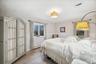 Bedroom featuring wood finished floors, crown molding, and a wainscoted wall