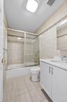 Full bath featuring vanity, enclosed tub / shower combo, and tile walls