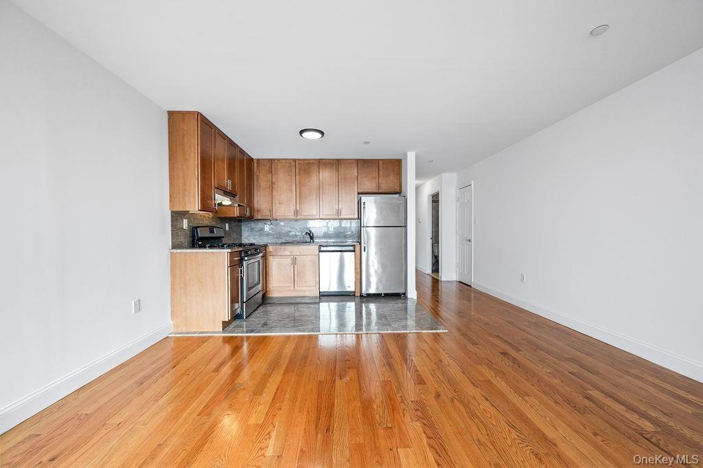 Kitchen featuring appliances with stainless steel finishes, tasteful backsplash, light wood finished floors, and under cabinet range hood