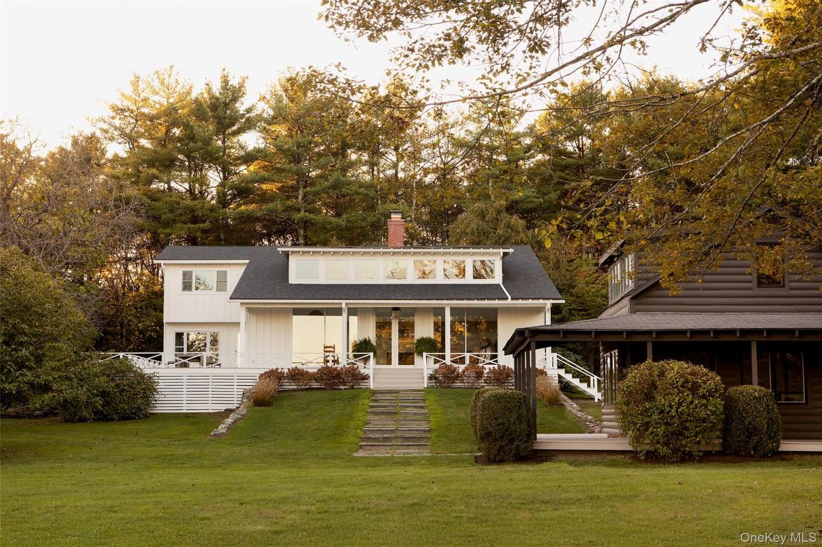 Rear view of house with a chimney, stairway, a lawn, covered porch, and view of wooded area