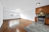 Kitchen with gas stove, under cabinet range hood, open floor plan, backsplash, and wood finished floors