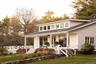 Back of property with covered porch, a lawn, stairway, a chimney, and a shingled roof