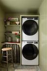 Laundry area with stacked washer and clothes dryer and wood walls