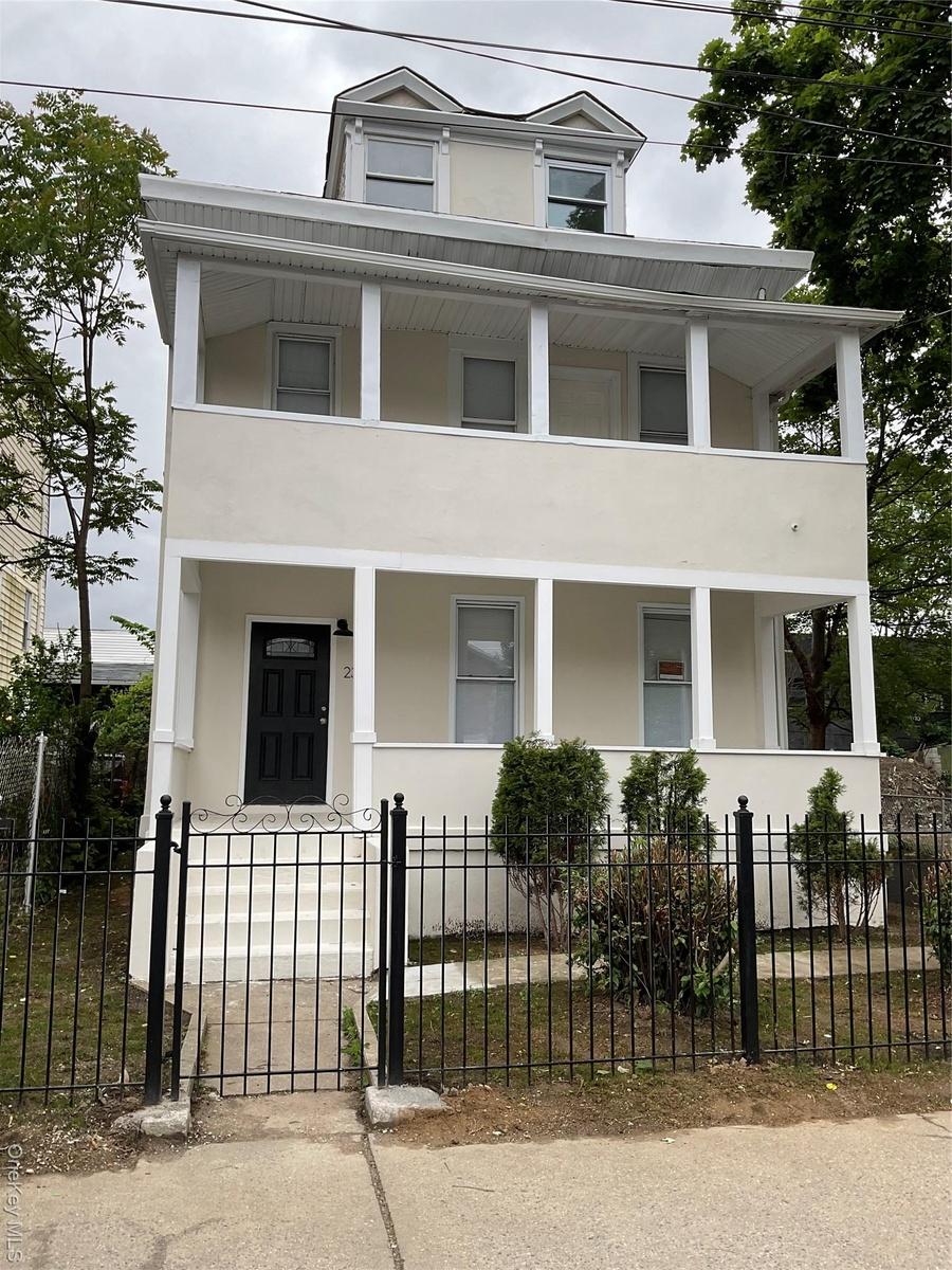 View of front facade featuring a porch, stucco siding, and a balcony