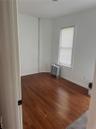 Unfurnished room featuring radiator heating unit, hardwood / wood-style flooring, and baseboards