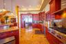 Kitchen featuring reddish brown cabinets, exhaust hood, light stone countertops, built in appliances, and recessed lighting
