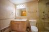 Bathroom with tile walls, radiator, vanity, a stall shower, and light tile patterned floors
