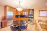 Kitchen with stainless steel appliances, decorative backsplash, radiator, wall chimney range hood, and brown cabinetry
