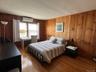 Bedroom featuring wood walls, dark wood-style flooring, and a wall mounted AC