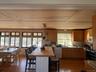 Kitchen featuring dark wood-style flooring, white appliances, a breakfast bar, a peninsula, and recessed lighting
