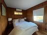 Bedroom featuring wood walls, wood finished floors, and a wall mounted air conditioner