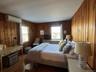 Bedroom featuring wood finished floors, multiple windows, wood walls, and an AC wall unit