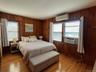 Bedroom with wooden walls, light wood-type flooring, a wall unit AC, and cooling unit
