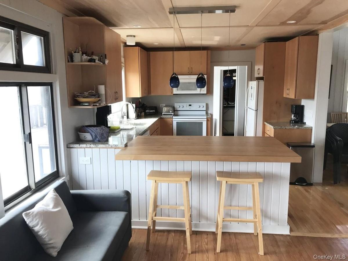 Kitchen featuring a peninsula, white appliances, light wood-type flooring, a kitchen breakfast bar, and pendant lighting
