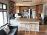 Kitchen featuring a peninsula, white appliances, light wood-type flooring, a kitchen breakfast bar, and pendant lighting