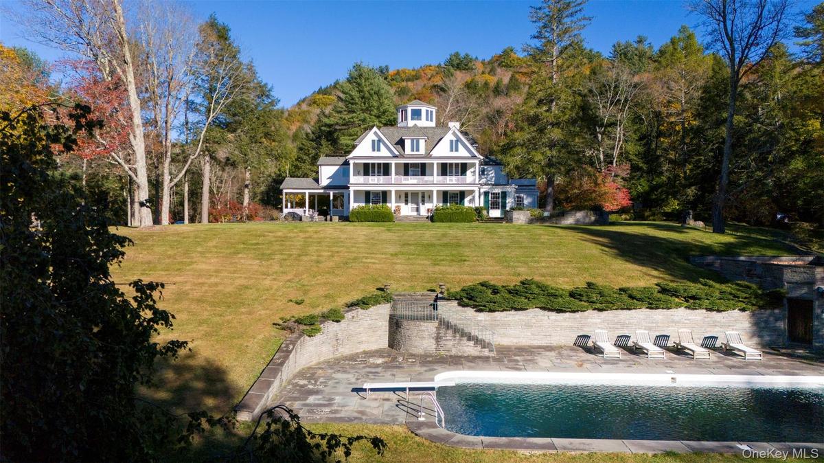 Back of house featuring a patio area, a yard, an outdoor pool, and a balcony