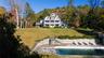 Back of house featuring a patio area, a yard, an outdoor pool, and a balcony