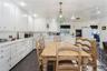 Kitchen with white appliances, white cabinetry, decorative light fixtures, and dark tile patterned floors