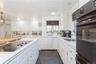 Kitchen featuring sink, white cabinetry, black appliances, and pendant lighting