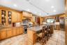 Kitchen featuring high quality appliances, arched walkways, recessed lighting, a center island with sink, and light stone countertops