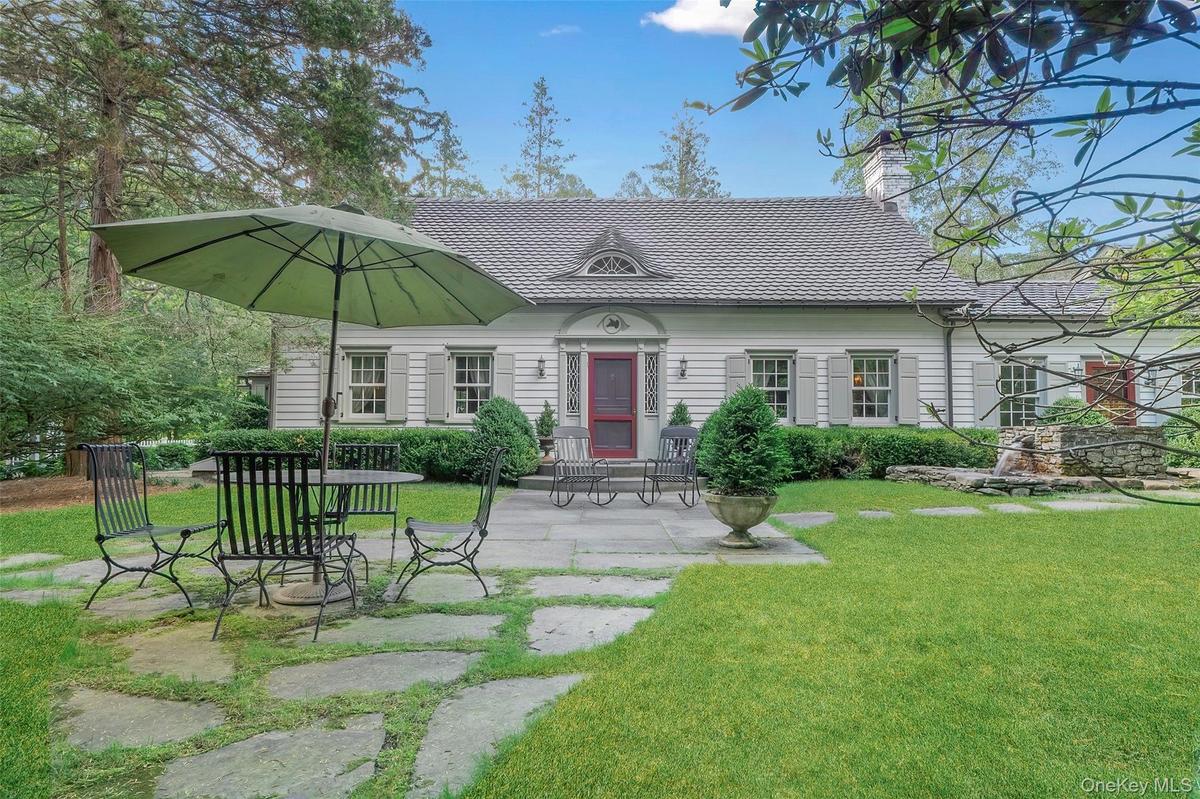 View of front of property featuring a front lawn, a chimney, and a patio