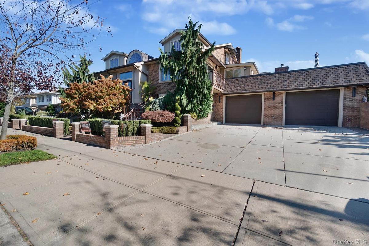 View of front of house featuring brick siding, concrete driveway, an attached garage, and a high end roof