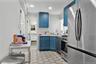Kitchen featuring stainless steel appliances, blue cabinets, tasteful backsplash, and light floors