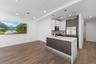 Kitchen with dark brown cabinetry, light stone countertops, hanging light fixtures, backsplash, and white cabinets