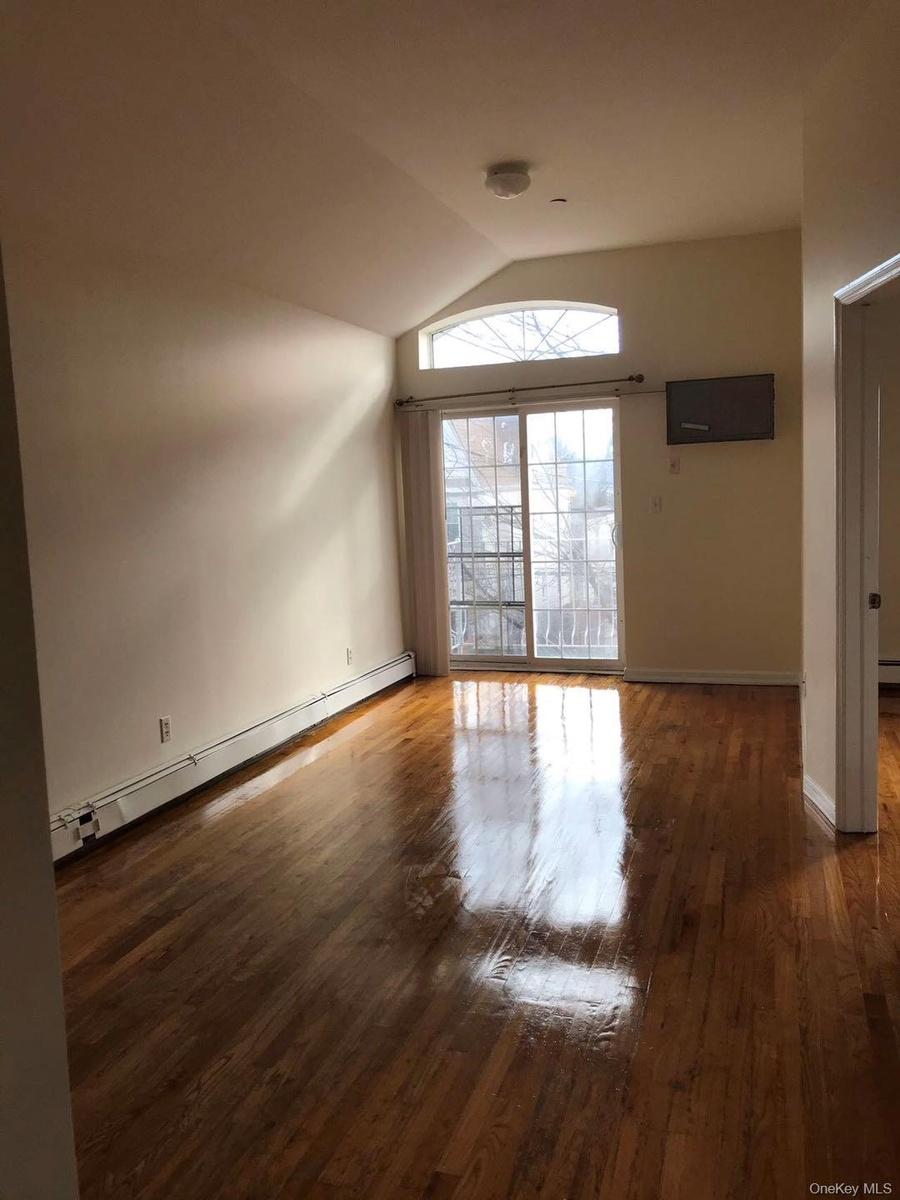 Unfurnished living room featuring a baseboard heating unit, dark wood finished floors, and lofted ceiling