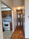 Kitchen featuring white range with gas stovetop, light countertops, light wood finished floors, under cabinet range hood, and brown cabinetry