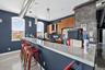 Kitchen with a breakfast bar, brown cabinets, hanging light fixtures, stainless steel gas range oven, and concrete flooring