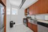 Kitchen featuring brown cabinetry, stainless steel appliances, light tile patterned floors, and wall chimney range hood
