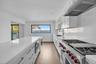 Kitchen featuring white cabinetry, range with two ovens, exhaust hood, recessed lighting, and wood finished floors