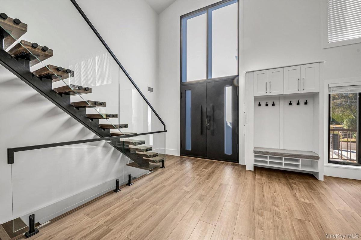 Foyer with stairs, a towering ceiling, and light wood-type flooring