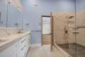 Full bath with double vanity and a marble finish shower