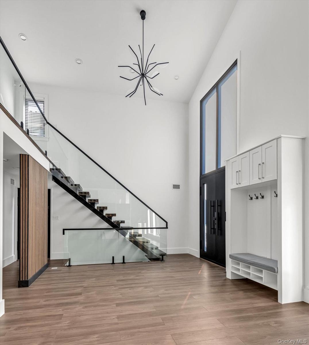 Entryway with plenty of natural light, a towering ceiling, a chandelier, light wood finished floors, and stairs