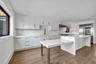Kitchen featuring white cabinets, light wood-style floors, stainless steel built in fridge, a breakfast bar, and light stone counters