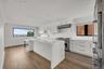 Kitchen featuring white cabinetry, light stone counters, high end appliances, a center island, and recessed lighting