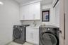 Laundry area featuring tile walls, cabinet space, light tile patterned floors, and washing machine and dryer
