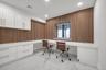 Office area with built in desk, recessed lighting, light marble finish flooring, and wood walls