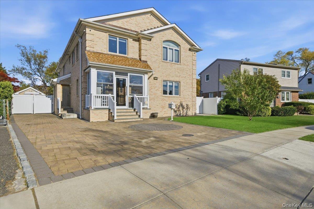 Back of house featuring brick siding, a gate, and a garage