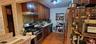Kitchen featuring stainless steel appliances, tasteful backsplash, light wood-style floors, under cabinet range hood, and dark brown cabinetry
