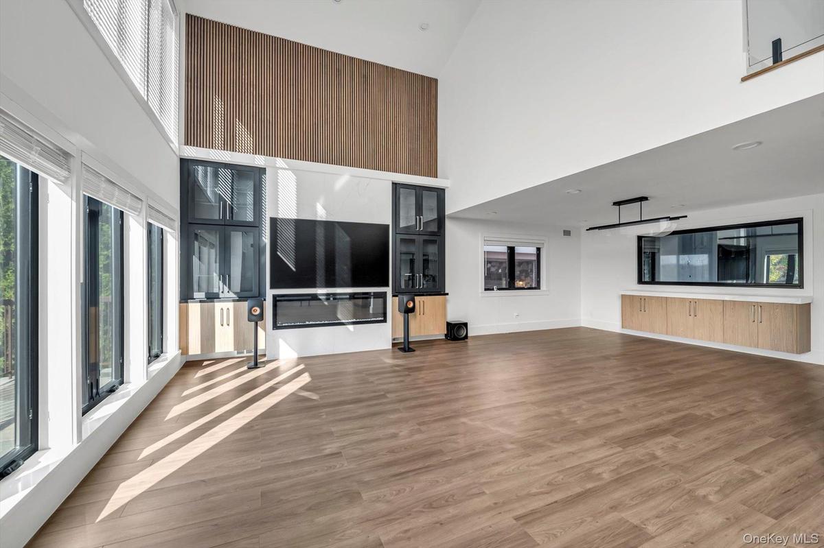 Unfurnished living room with a towering ceiling and light wood-type flooring